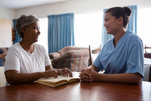 Nurse talking to senior women while sitting at table in nursing home